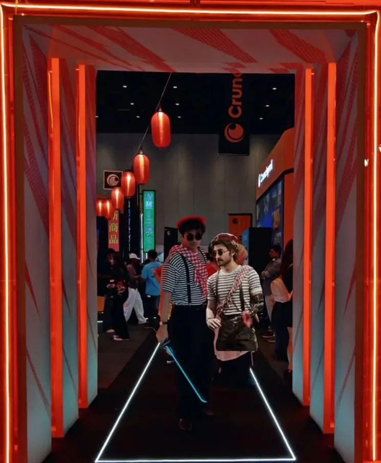 Two striped red-beret costumes posing inside a red illuminated convention frame